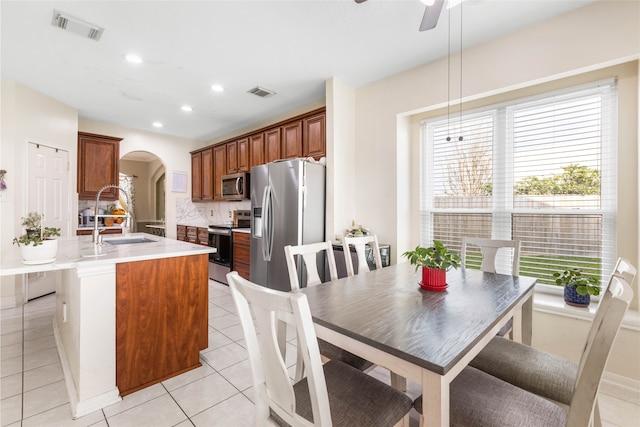 23602 Hawkins Creek Ct, Katy, TX 77494 - kitchen featuring appliances with stainless steel finishes, arched walkways, tasteful backsplash, light countertops, and a ceiling fan