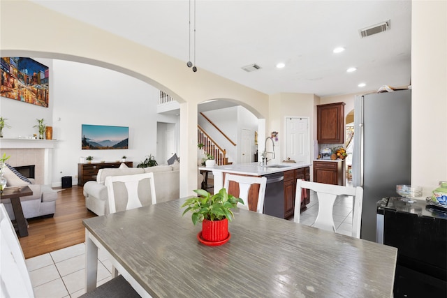 23602 Hawkins Creek Ct, Katy, TX 77494 - dining space featuring recessed lighting, stairway, a tiled fireplace, light tile patterned flooring, and arched walkways