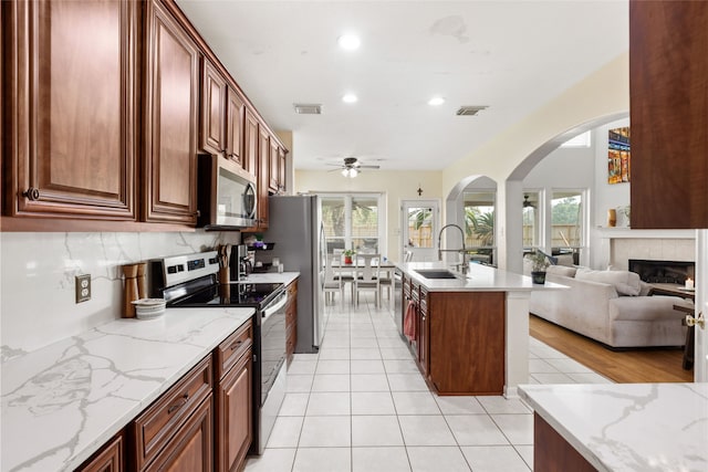 23602 Hawkins Creek Ct, Katy, TX 77494 - kitchen with appliances with stainless steel finishes, arched walkways, a ceiling fan, recessed lighting, and light tile patterned flooring