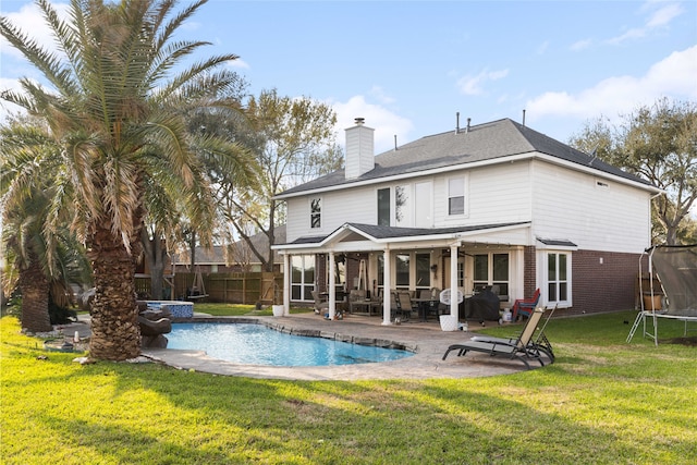 23602 Hawkins Creek Ct, Katy, TX 77494 - rear view of property featuring a chimney, a trampoline, a patio area, a fenced backyard, and brick siding
