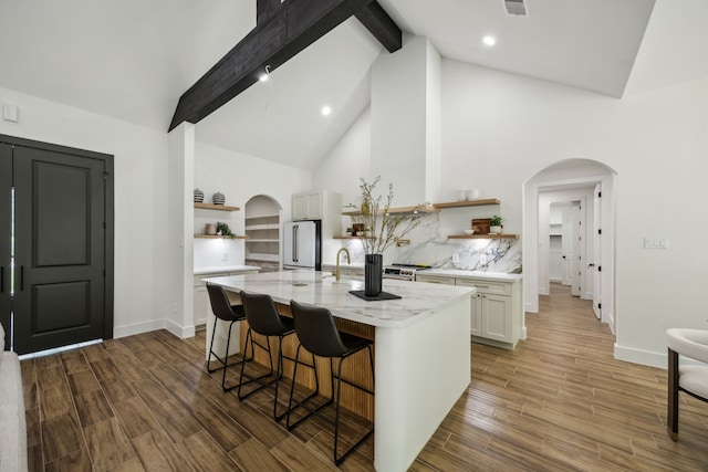 1265 Rd 66112, Dayton, TX 77535 - kitchen with open shelves, freestanding refrigerator, arched walkways, beam ceiling, and wood finished floors