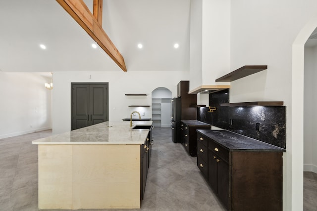 1253 Rd 66112, Dayton, TX 77535 - kitchen featuring arched walkways, a center island with sink, high vaulted ceiling, freestanding refrigerator, and light stone counters