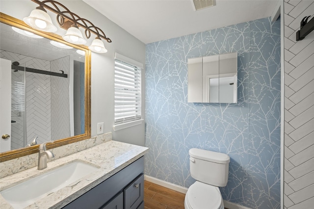3835 Tartan Ln, Houston, TX 77025 - bathroom with wood finished floors, wallpapered walls, vanity, and a stall shower