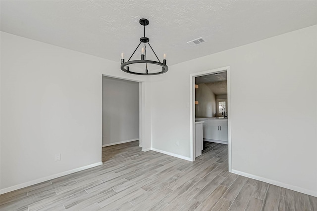 2330 Grindstone Ln, Sugar Land, TX 77498 - unfurnished dining area featuring light wood finished floors, a chandelier, and a textured ceiling