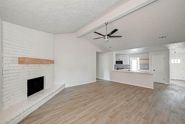 2330 Grindstone Ln, Sugar Land, TX 77498 - unfurnished living room featuring light wood-type flooring, a textured ceiling, a fireplace, and a ceiling fan