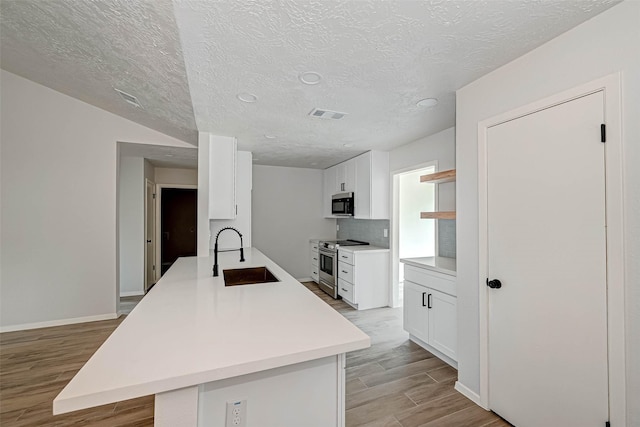 2330 Grindstone Ln, Sugar Land, TX 77498 - kitchen featuring stainless steel range with electric stovetop, light wood finished floors, open shelves, white cabinets, and a textured ceiling