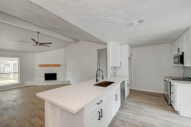 2330 Grindstone Ln, Sugar Land, TX 77498 - kitchen with stainless steel appliances, light wood finished floors, a ceiling fan, a peninsula, and light countertops