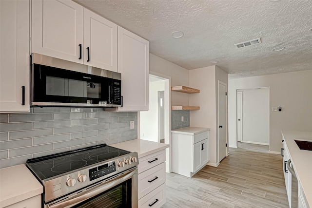 2330 Grindstone Ln, Sugar Land, TX 77498 - kitchen featuring stainless steel appliances, open shelves, white cabinetry, light countertops, and light wood-style floors