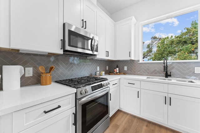1428 Miller St, Houston, TX 77003 - kitchen with stainless steel appliances, backsplash, white cabinets, and light wood-style flooring