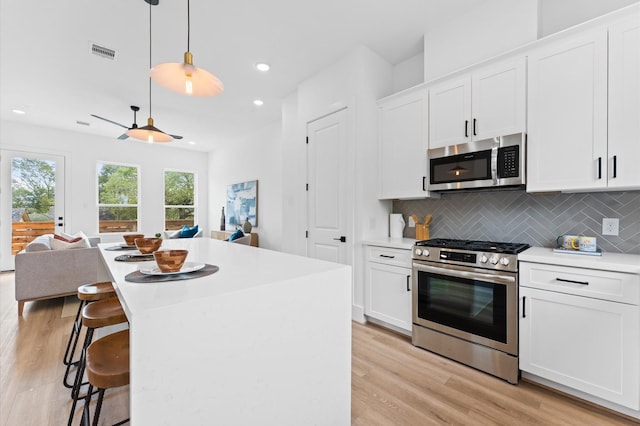 1428 Miller St, Houston, TX 77003 - kitchen featuring stainless steel appliances, light wood-style flooring, backsplash, light countertops, and white cabinets