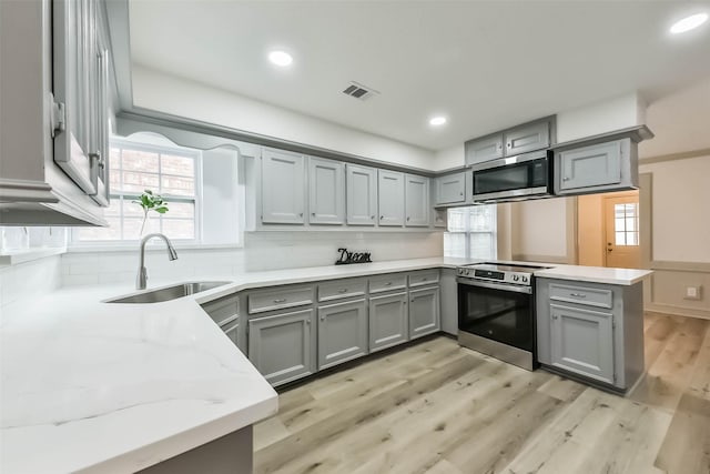 4214 Brightwood Dr, Houston, TX 77068 - kitchen featuring appliances with stainless steel finishes, gray cabinetry, a peninsula, light wood finished floors, and recessed lighting