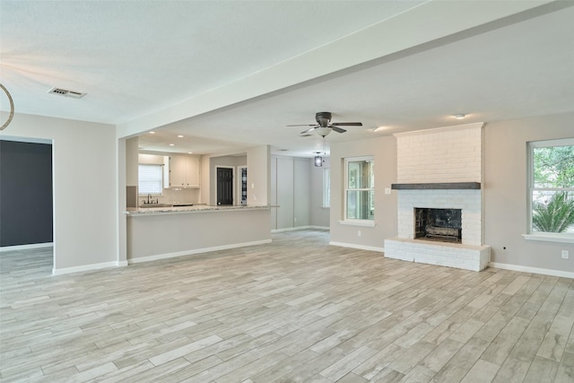 725 River Plantation Dr, Conroe, TX 77302 - unfurnished living room with light wood-type flooring, a fireplace, and a ceiling fan