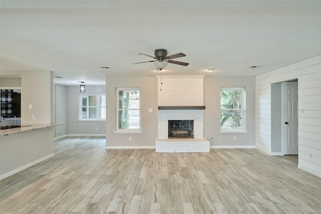 725 River Plantation Dr, Conroe, TX 77302 - unfurnished living room featuring light wood-style floors, ceiling fan, and a brick fireplace
