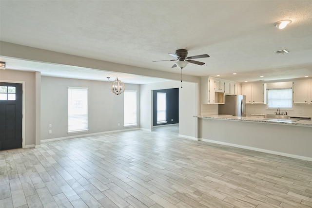 725 River Plantation Dr, Conroe, TX 77302 - kitchen featuring freestanding refrigerator, a chandelier, light stone countertops, ceiling fan, and light wood-style flooring