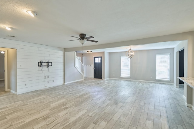 725 River Plantation Dr, Conroe, TX 77302 - unfurnished living room featuring light wood finished floors, stairs, a ceiling fan, and wooden walls