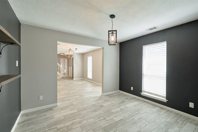 725 River Plantation Dr, Conroe, TX 77302 - unfurnished room featuring a chandelier, light wood-style floors, and a textured ceiling