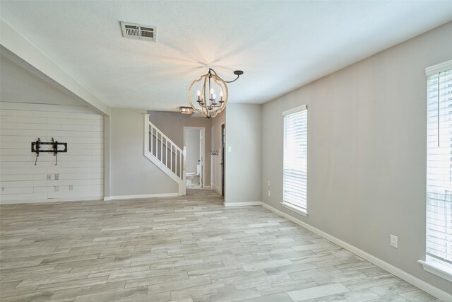 725 River Plantation Dr, Conroe, TX 77302 - unfurnished room with stairway, plenty of natural light, light wood-style flooring, and a chandelier