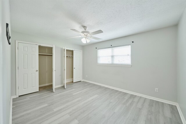725 River Plantation Dr, Conroe, TX 77302 - unfurnished bedroom with multiple closets, a textured ceiling, light wood-style floors, and a ceiling fan