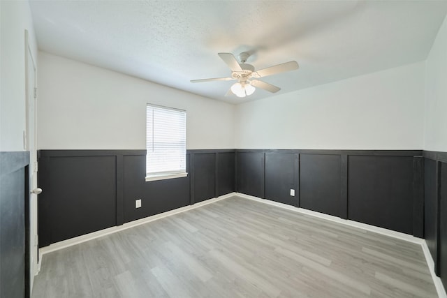 725 River Plantation Dr, Conroe, TX 77302 - unfurnished room with wainscoting, a ceiling fan, wood finished floors, a decorative wall, and a textured ceiling
