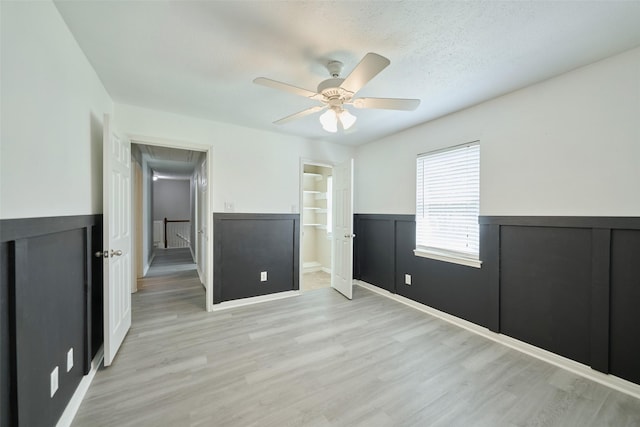 725 River Plantation Dr, Conroe, TX 77302 - unfurnished bedroom featuring attic access, a wainscoted wall, light wood-style floors, ceiling fan, and a textured ceiling