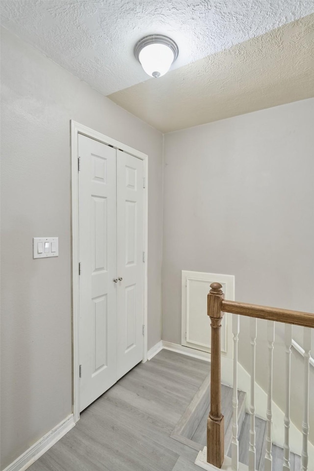 725 River Plantation Dr, Conroe, TX 77302 - corridor featuring light wood finished floors, a textured ceiling, and an upstairs landing