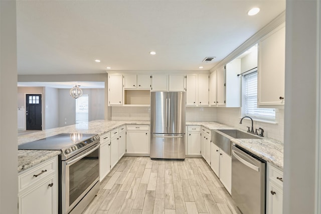 725 River Plantation Dr, Conroe, TX 77302 - kitchen featuring appliances with stainless steel finishes, light stone counters, light wood-style floors, white cabinetry, and recessed lighting