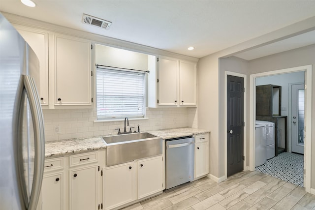 725 River Plantation Dr, Conroe, TX 77302 - kitchen with appliances with stainless steel finishes, separate washer and dryer, light wood-style flooring, tasteful backsplash, and white cabinets