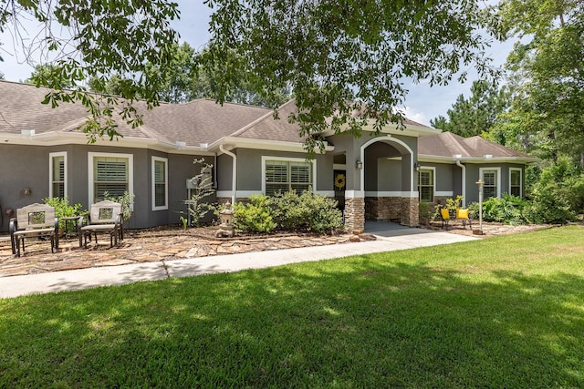 27724 Colapis Dr, Splendora, TX 77372 - view of front of house with stucco siding, a front yard, a shingled roof, and stone siding