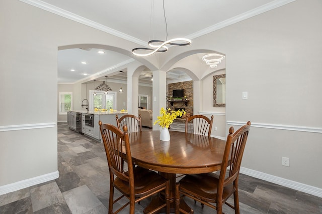27724 Colapis Dr, Splendora, TX 77372 - dining area with crown molding, a chandelier, a fireplace, and arched walkways