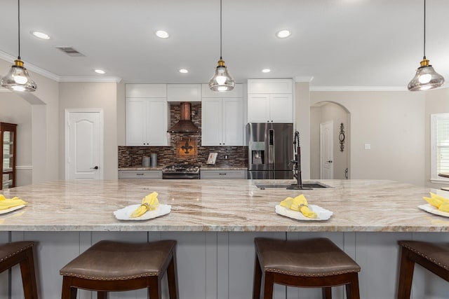 27724 Colapis Dr, Splendora, TX 77372 - kitchen with appliances with stainless steel finishes, premium range hood, arched walkways, ornamental molding, and white cabinetry