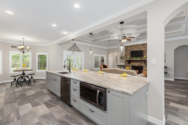 27724 Colapis Dr, Splendora, TX 77372 - kitchen with appliances with stainless steel finishes, arched walkways, a stone fireplace, ornamental molding, and a ceiling fan