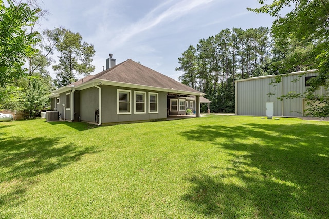 27724 Colapis Dr, Splendora, TX 77372 - back of house with a lawn, a chimney, an outdoor structure, and a pole building