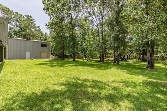 27724 Colapis Dr, Splendora, TX 77372 - view of grassy yard with a garage and view of wooded area