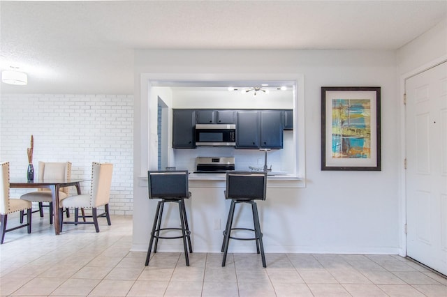 2429 Briarwest Blvd, Houston, TX 77077 - kitchen with stainless steel appliances, a breakfast bar, light countertops, a peninsula, and light tile patterned floors