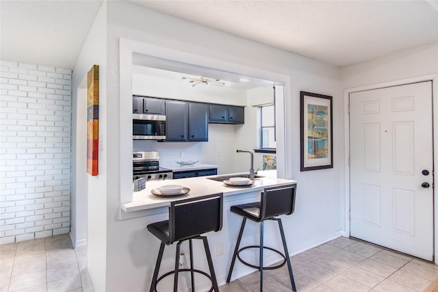 2429 Briarwest Blvd, Houston, TX 77077 - kitchen with appliances with stainless steel finishes, light countertops, a kitchen bar, and light tile patterned flooring