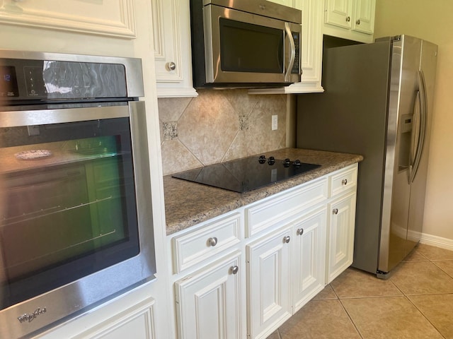 6220 Queenswood Ln, Houston, TX 77008 - kitchen with stainless steel appliances, decorative backsplash, light tile patterned floors, light stone countertops, and white cabinets
