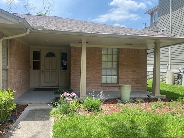6220 Queenswood Ln, Houston, TX 77008 - doorway to property featuring brick siding, covered porch, and a shingled roof