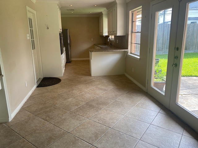 6220 Queenswood Ln, Houston, TX 77008 - kitchen with crown molding, light tile patterned floors, french doors, white cabinetry, and freestanding refrigerator