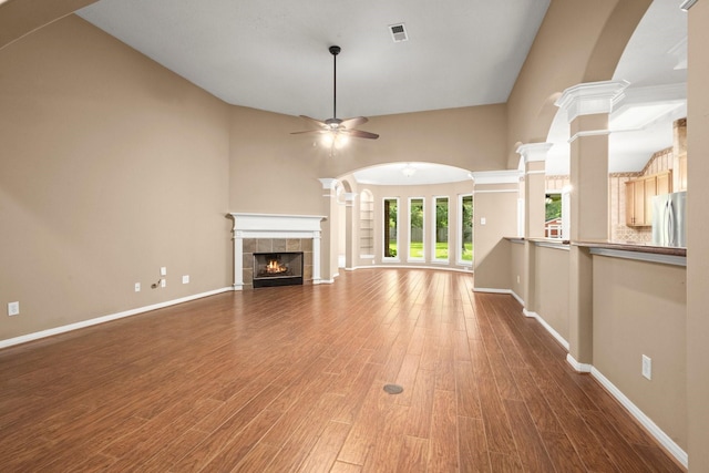 31406 Spica St, Tomball, TX 77375 - unfurnished living room featuring a ceiling fan, wood finished floors, a tiled fireplace, and a high ceiling