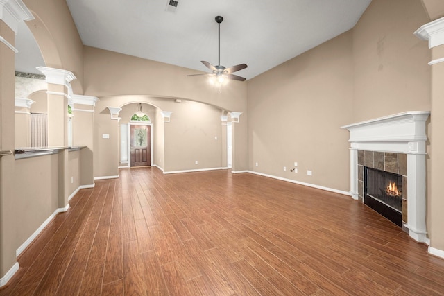 31406 Spica St, Tomball, TX 77375 - unfurnished living room with ceiling fan, a tile fireplace, high vaulted ceiling, wood finished floors, and decorative columns