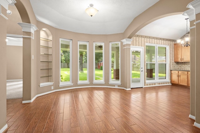 31406 Spica St, Tomball, TX 77375 - unfurnished dining area featuring built in features, arched walkways, wood finished floors, and decorative columns