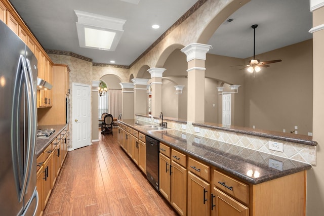 31406 Spica St, Tomball, TX 77375 - kitchen featuring appliances with stainless steel finishes, ceiling fan, under cabinet range hood, light wood-style floors, and dark stone counters