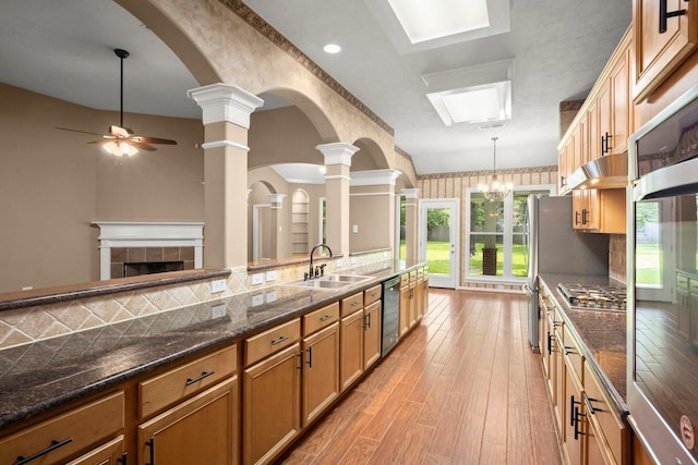 31406 Spica St, Tomball, TX 77375 - kitchen with dishwasher, ceiling fan, light wood finished floors, decorative light fixtures, and a fireplace