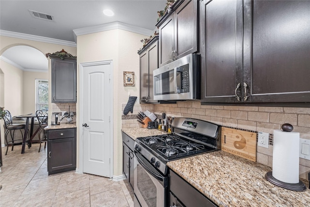 24111 Auburn Woods Ct, Porter, TX 77365 - kitchen with appliances with stainless steel finishes, arched walkways, decorative backsplash, light stone countertops, and ornamental molding