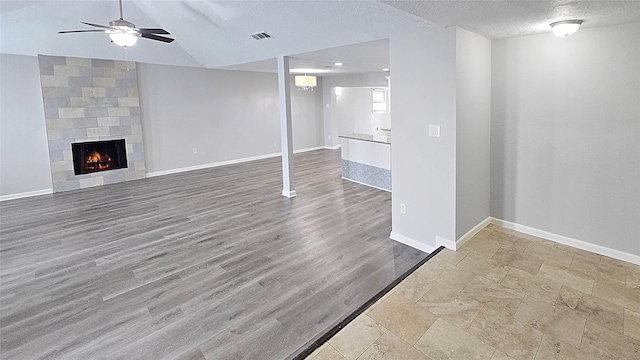 2414 Stillmeadow Dr, Missouri City, TX 77489 - below grade area with ceiling fan, a textured ceiling, a tile fireplace, and wood finished floors
