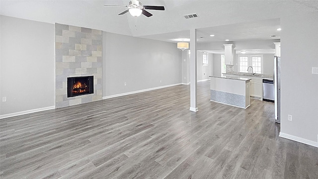 2414 Stillmeadow Dr, Missouri City, TX 77489 - unfurnished living room featuring ceiling fan, light wood-type flooring, recessed lighting, and a tiled fireplace