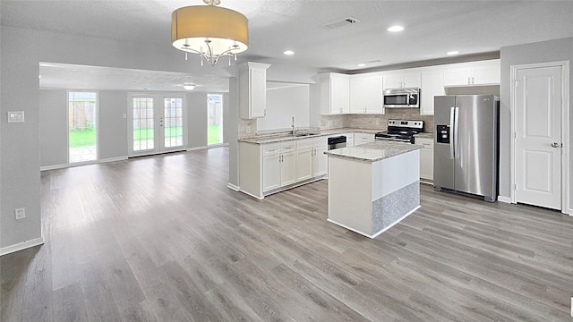 2414 Stillmeadow Dr, Missouri City, TX 77489 - kitchen with appliances with stainless steel finishes, light wood-style floors, backsplash, a kitchen island, and recessed lighting