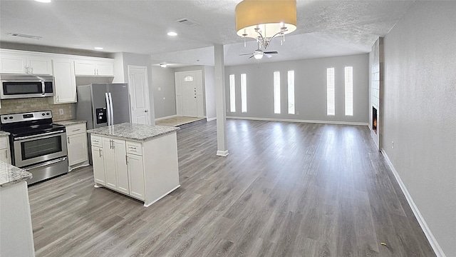 2414 Stillmeadow Dr, Missouri City, TX 77489 - kitchen featuring appliances with stainless steel finishes, light wood-style flooring, backsplash, white cabinets, and a center island