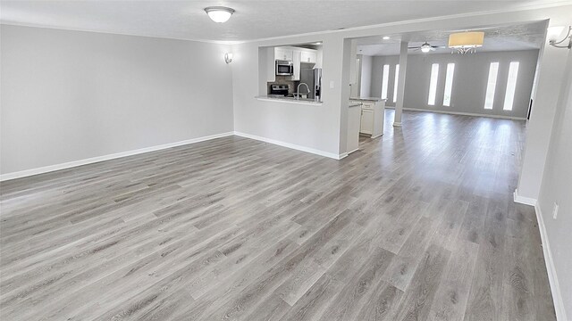 2414 Stillmeadow Dr, Missouri City, TX 77489 - unfurnished living room with light wood-style floors, ceiling fan, and crown molding