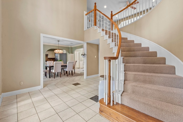 5507 Glenmere Ln, Spring, TX 77379 - stairway featuring a high ceiling, arched walkways, tile patterned floors, and a chandelier